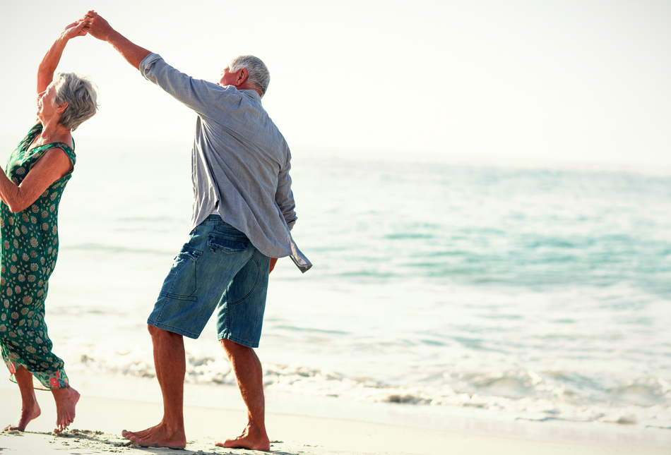 Retired couple dancing on a beach