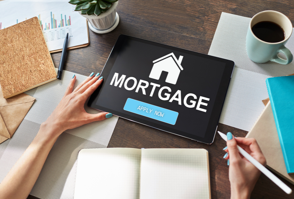 Desk filled with paperwork and tablet that says “mortgage”