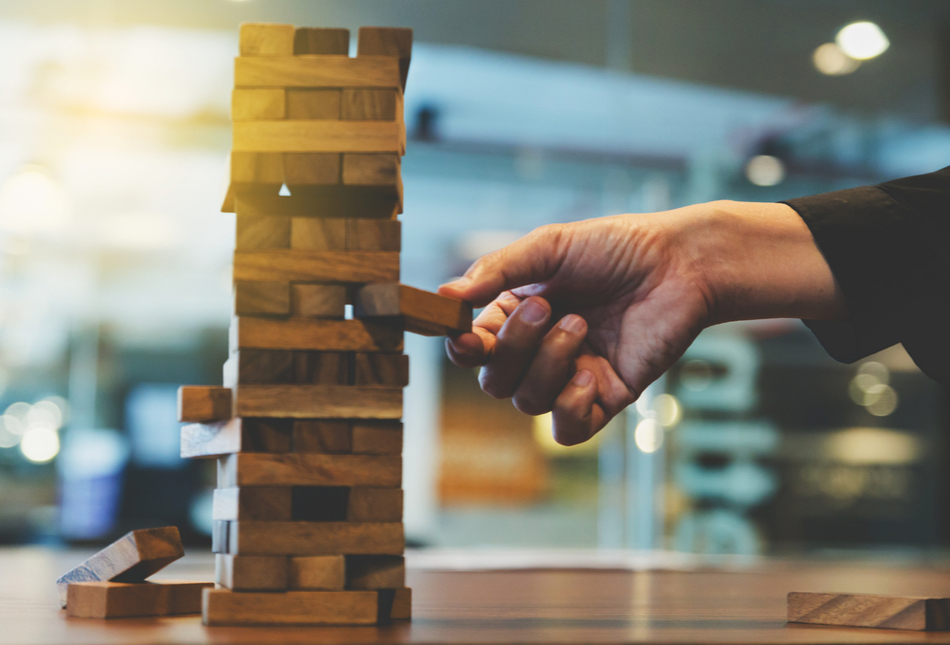 Hand removing a wooden block from a Jenga game
