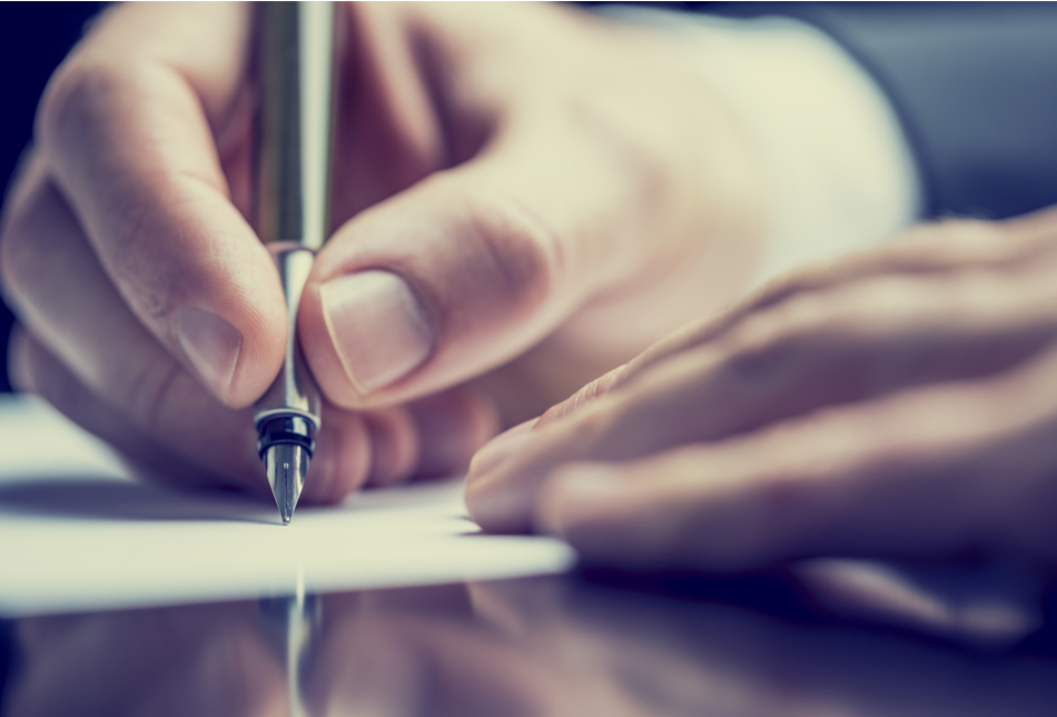 Close up of a hand holding a pen to paper