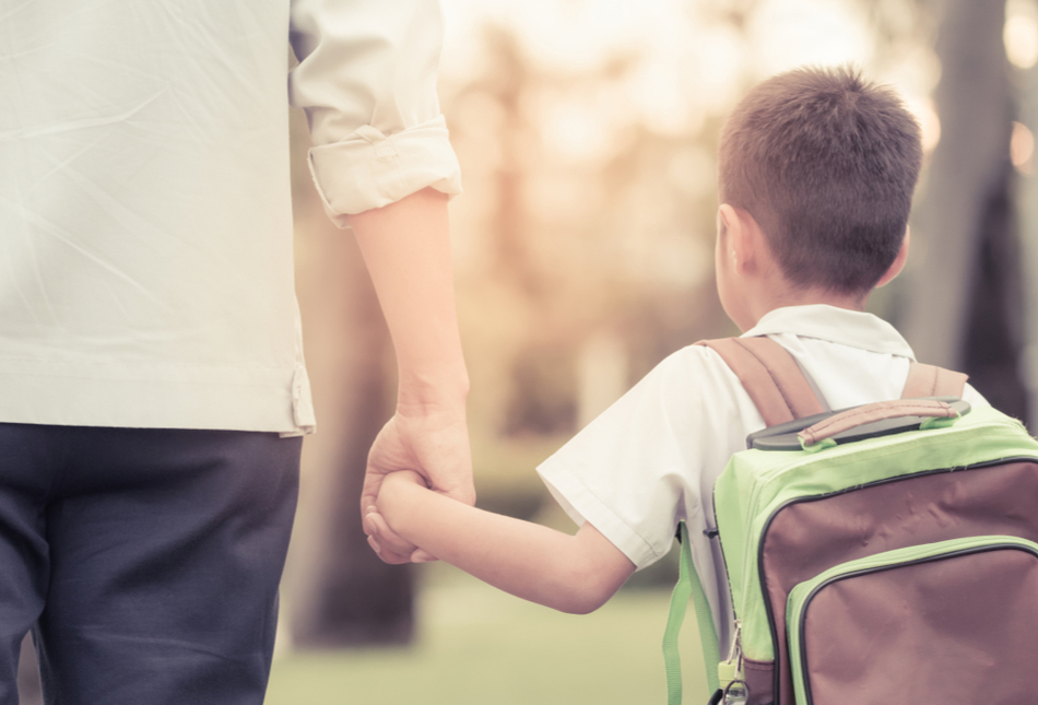 A father and son holding hands as they walk through a park