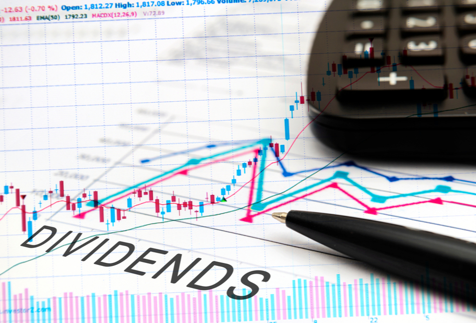 Paper showing a graph and the text “Dividends” with a calculator and pen