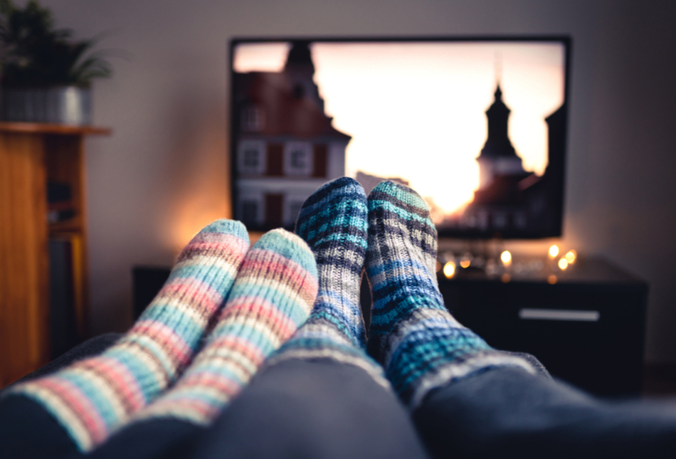 Two people sitting with their feet up while watching television