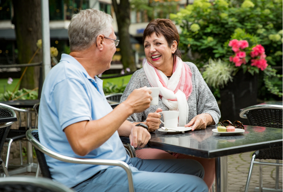 An older couple enjoying a cup of coffee outside at a café.