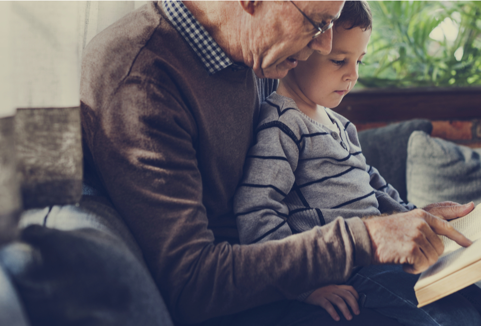 A grandfather and grandson reading a book together