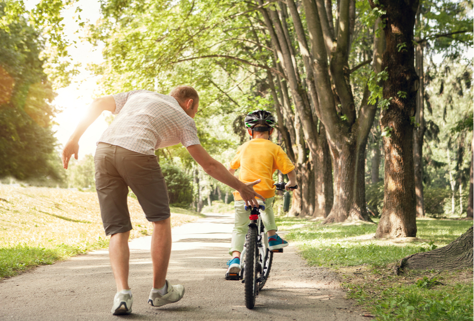A father teaching his young son to ride a bike.