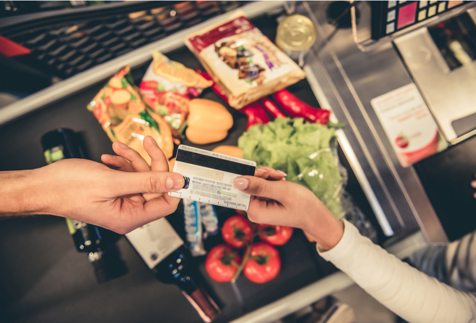A customer handing over a bank card to pay for goods in a supermarket.