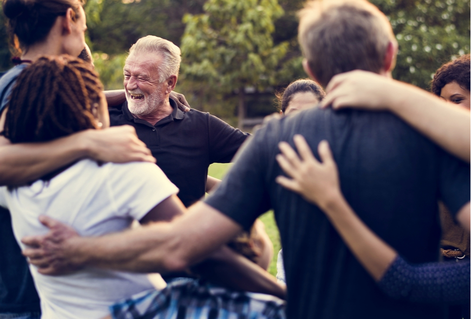 A group of people with their arms around each other laughing.