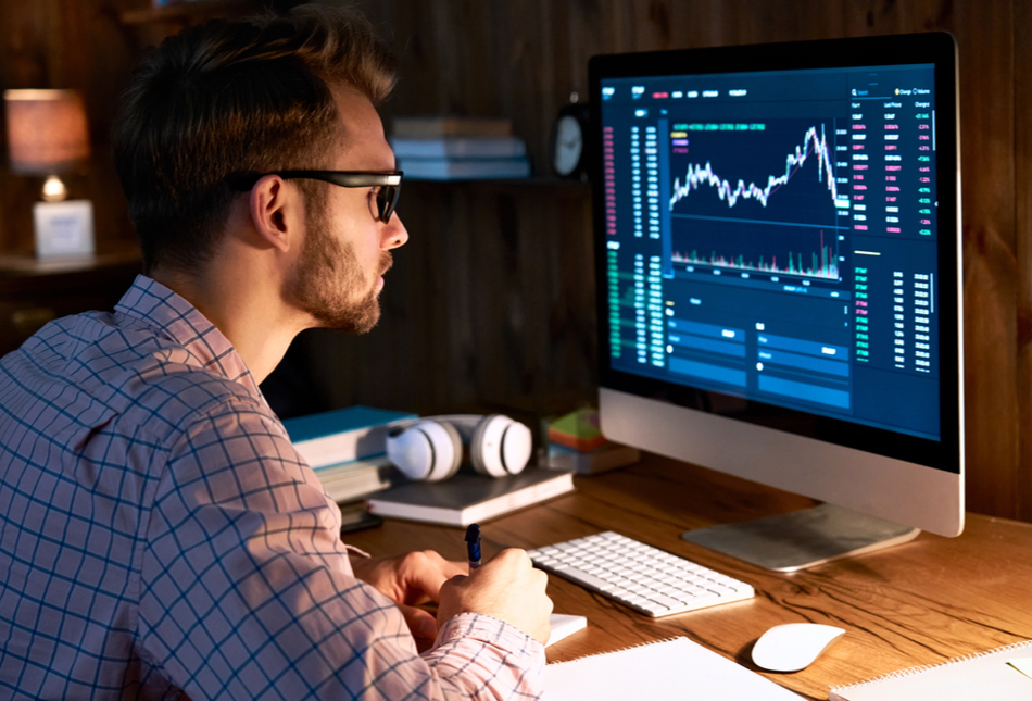 A man looking at graphs and data on a computer screen.