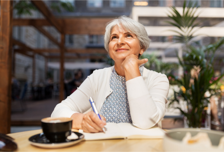 An older woman enjoying a cup of coffee and writing in a journal.