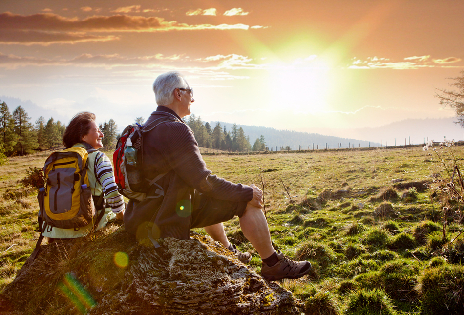 An older couple watching the sunrise on a hike.