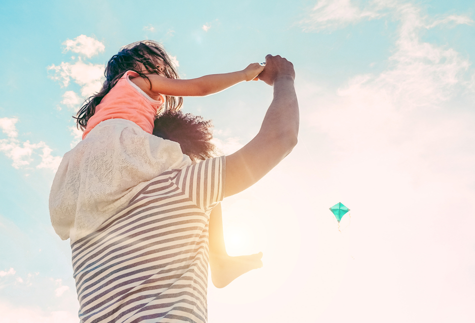 A father with his young daughter sitting on his shoulders.