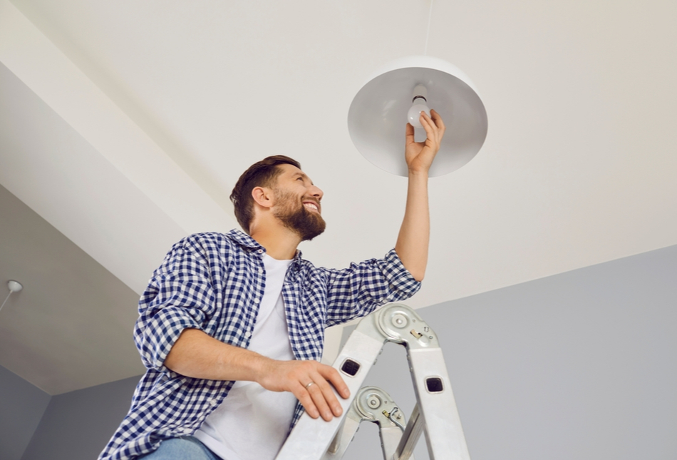 A man changing a lightbulb in his home.