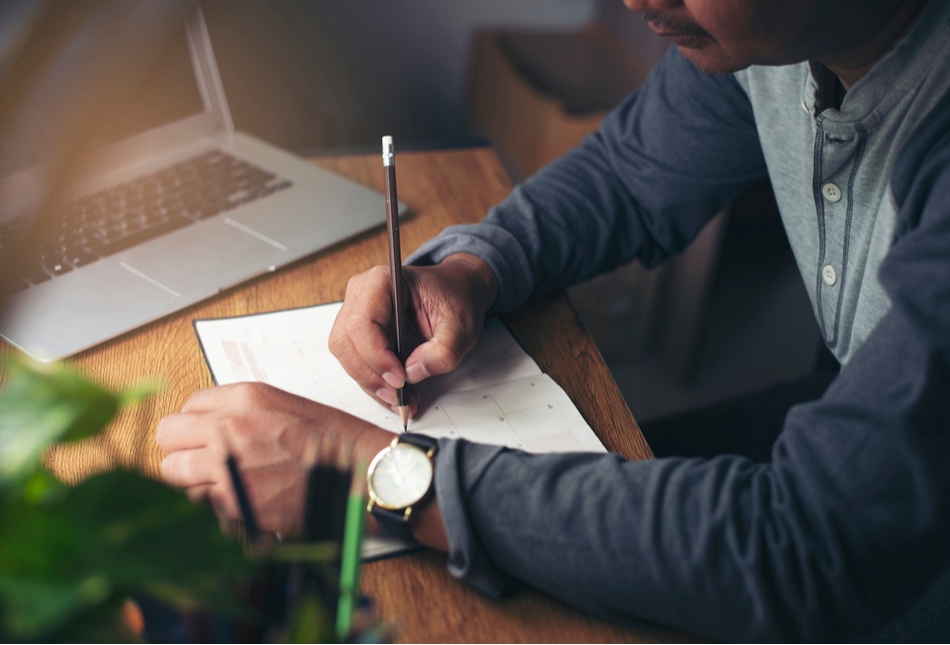 A man writing notes in a planner.