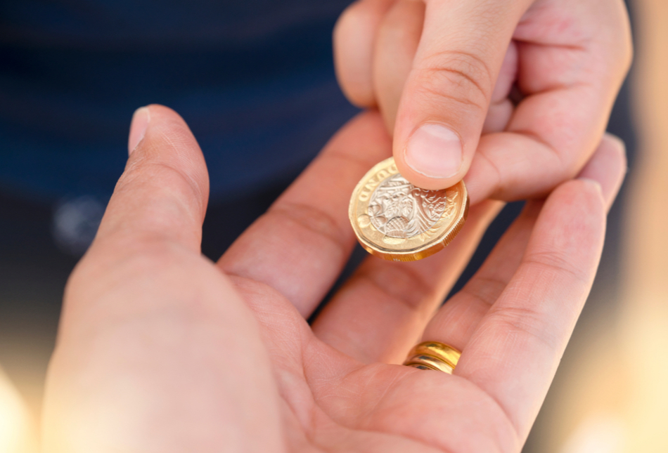 Someone passing a £1 coin to another person.
