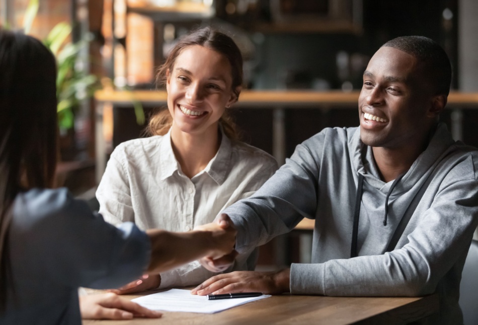 An estate agent shaking hands with a young couple.