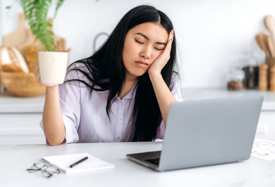 A woman falling asleep at her desk.