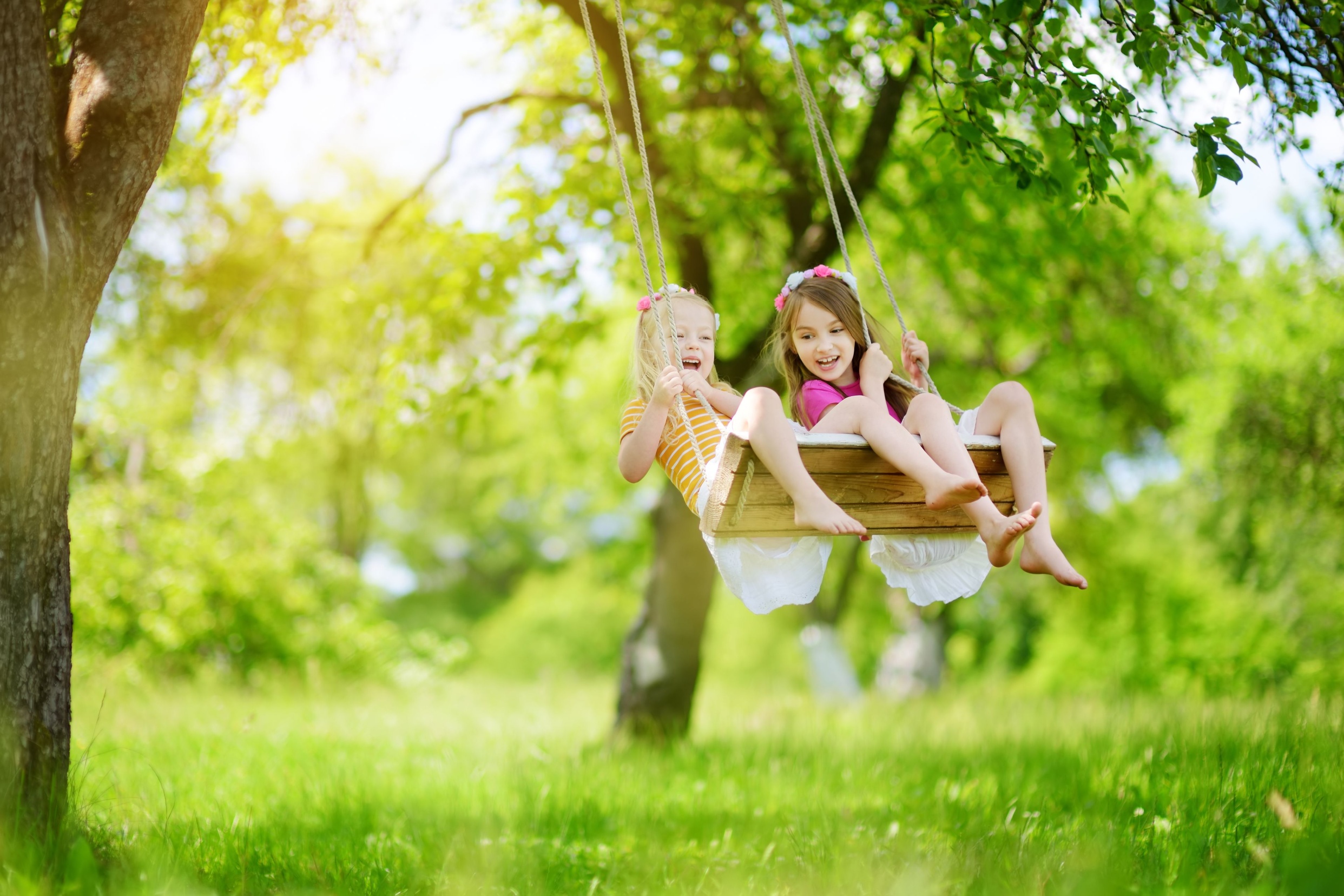 Two girls playing on a swing.