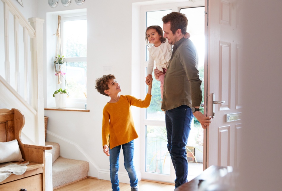 A father and two children walking into their home.