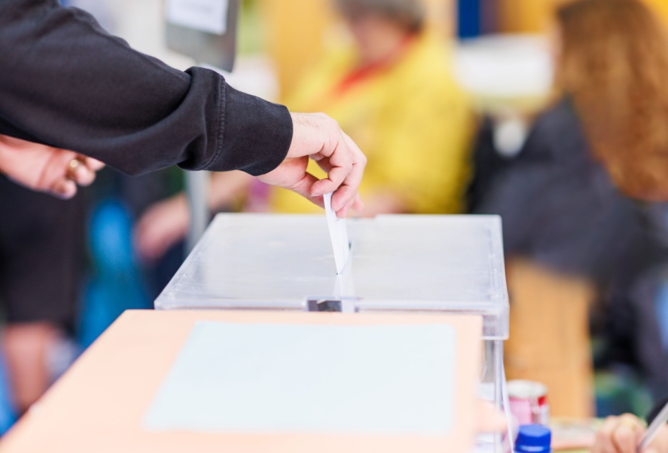 A man voting using a ballot box.