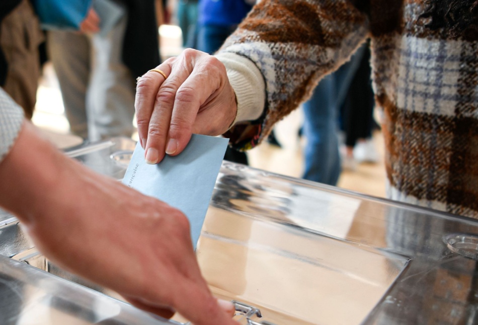 A person putting a ballot paper into a box.
