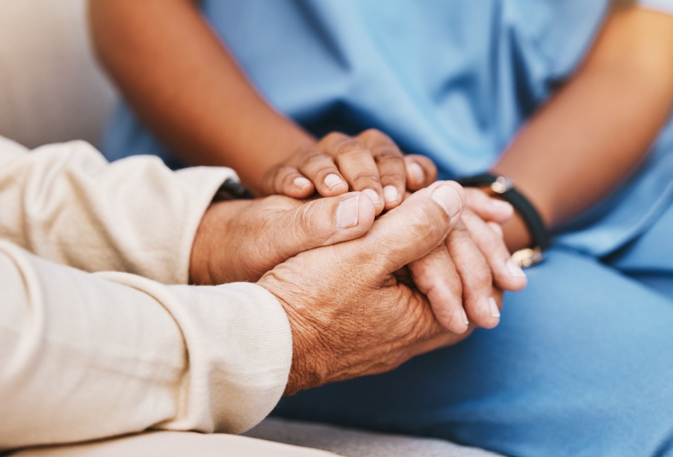 An elderly person holding hands with a nurse.