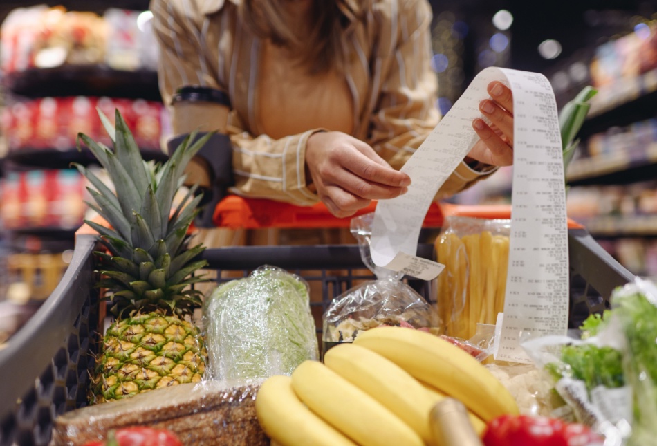 A woman looking at a receipt in a supermarket.