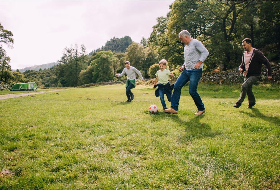 Multi-generational family playing football in a park.