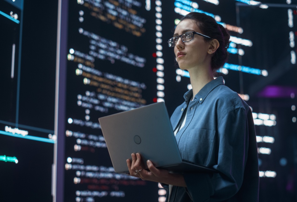 A woman surrounded by large screens with programming code.