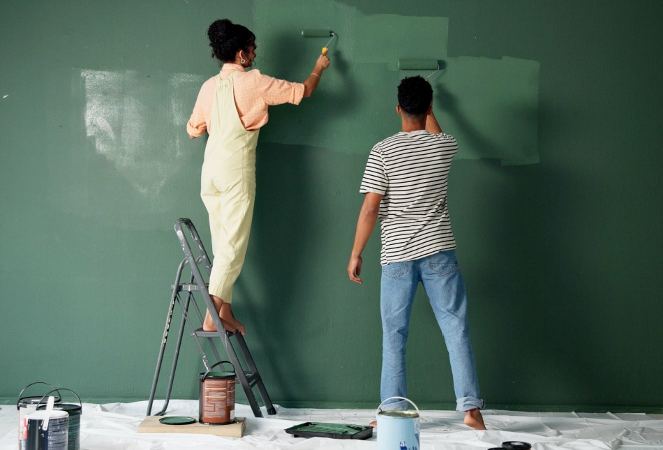 A couple painting a wall in their home.