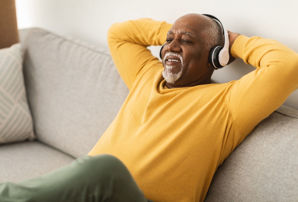 A man relaxing on a sofa with his hands behind his head.