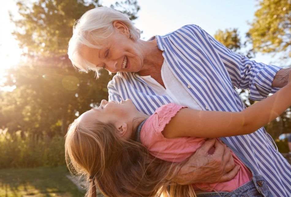A grandmother playing with her granddaughter outside.