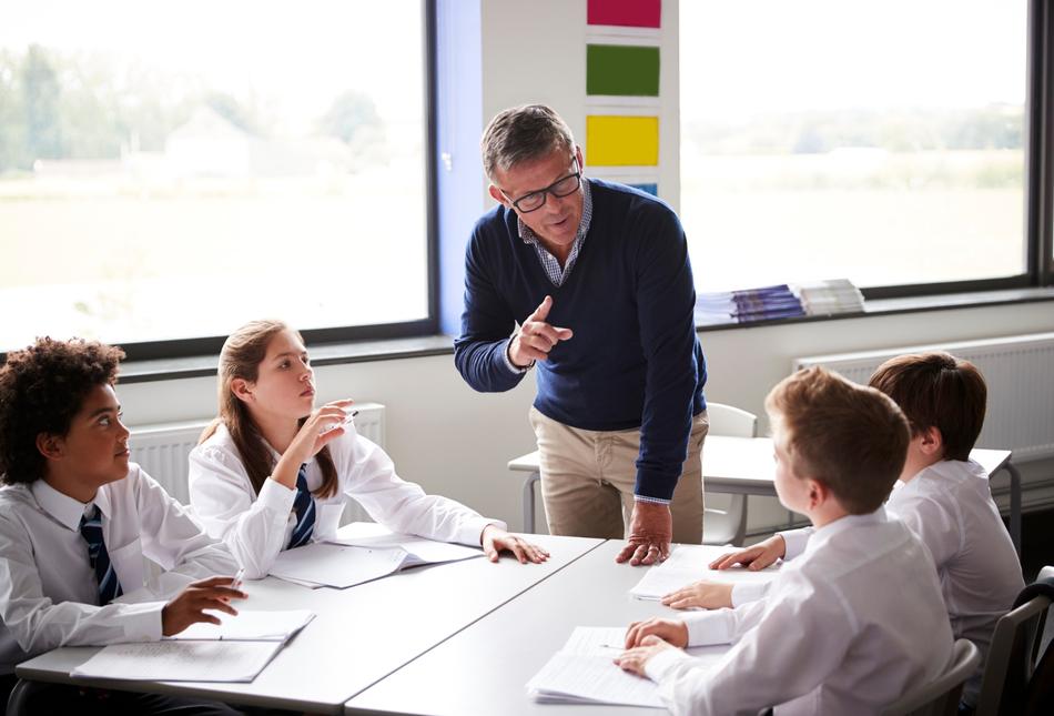 A teacher talking to a group of pupils in a classroom.