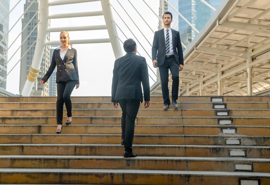 Three office workers crossing on some steps.