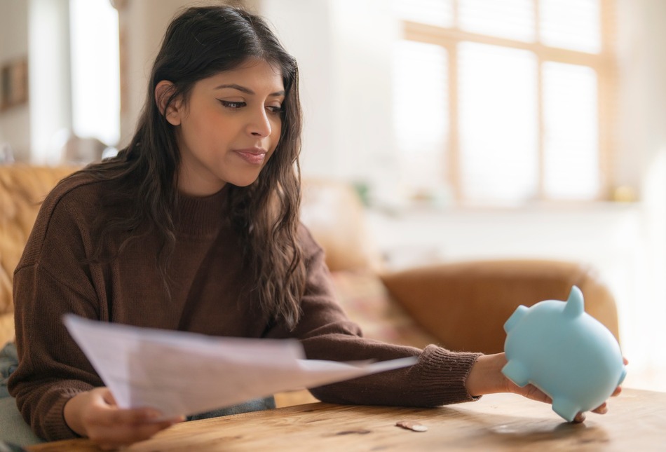 A woman holding a piggy bank and paperwork.