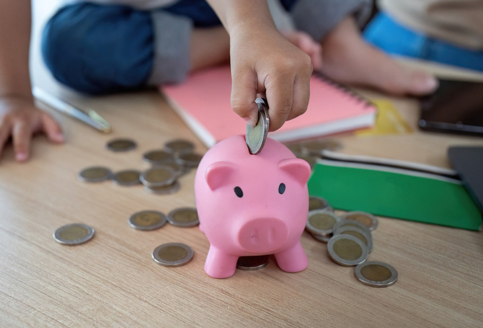 Child putting coins into a piggy bank