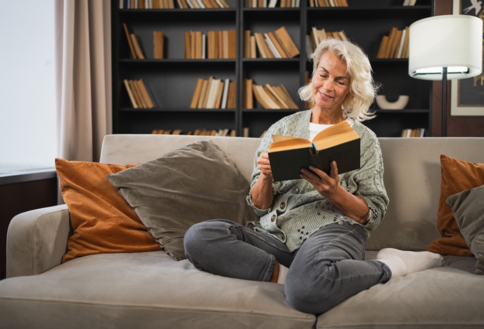 Smiling lady sitting on a sofa reading a book